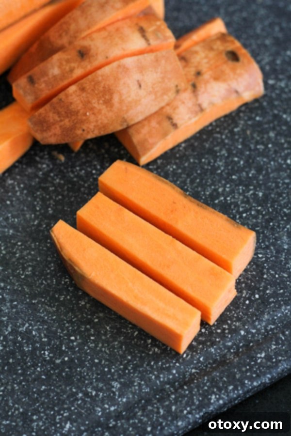Perfectly cut sweet potato wedges arranged on a wooden chopping board, ready for seasoning.