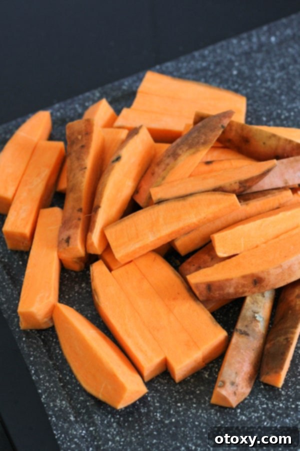 A generous pile of uniform sweet potato wedges displayed on a cutting board.