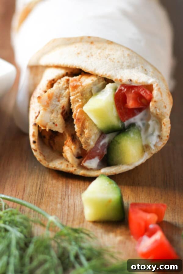A perfectly wrapped chicken gyro, held securely in parchment paper, ready to be enjoyed as a delicious and convenient meal.