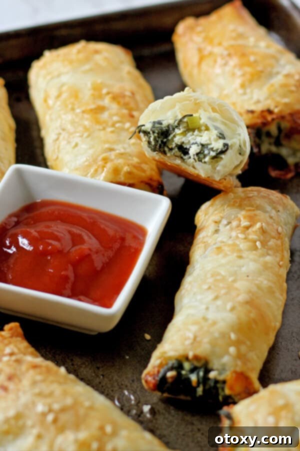 Spinach Ricotta Rolls Oven or Air Fried 2 Golden brown spinach and ricotta rolls arranged neatly on a baking tray, showcasing their flaky pastry and appealing texture.