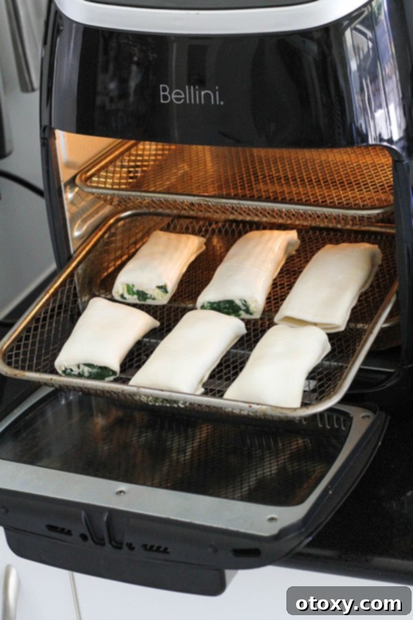 Spinach Ricotta Rolls Oven or Air Fried 11 Golden, crispy spinach and ricotta rolls cooking in an air fryer basket, showcasing their perfect texture and even browning.