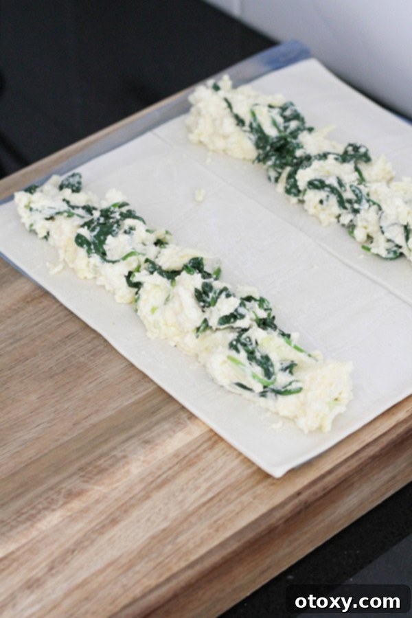 Spinach Ricotta Rolls Oven or Air Fried 7 Spinach and ricotta filling carefully laid in a log shape along one edge of a puff pastry sheet, ready to be rolled.