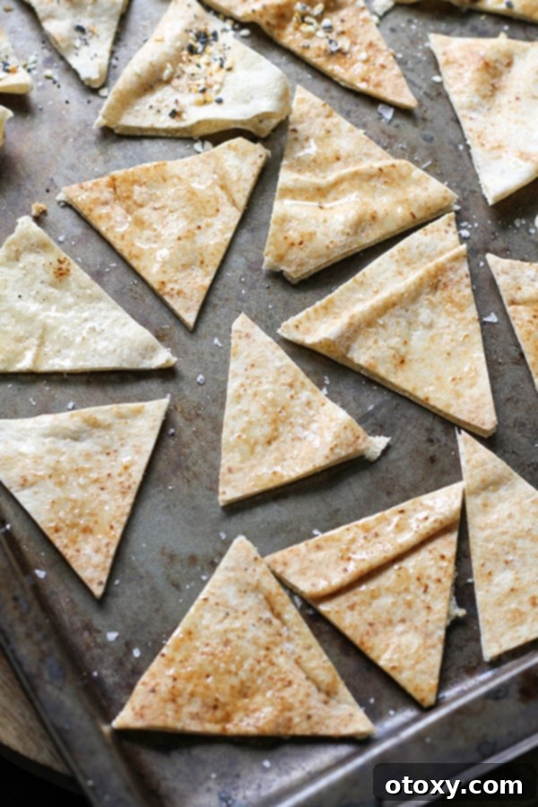 pita triangles on a baking tray ready to be baked. Unbaked pita triangles, lightly oiled and seasoned, are neatly arranged on a baking sheet, ready for the oven.