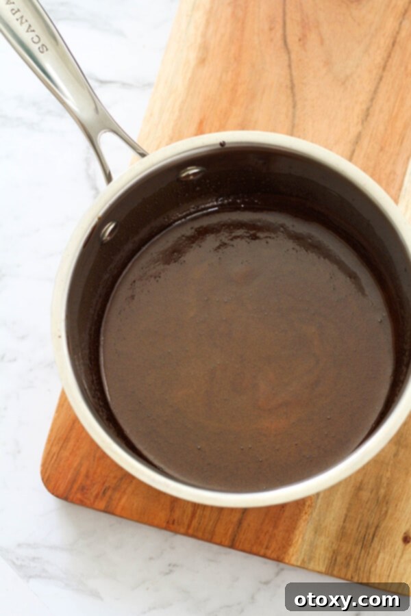 Balsamic glaze simmering gently in a steel saucepan on the stove, beginning to thicken.