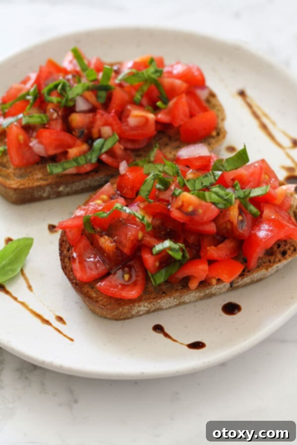 Two pieces of gourmet bruschetta on a white plate, beautifully drizzled with homemade balsamic glaze.