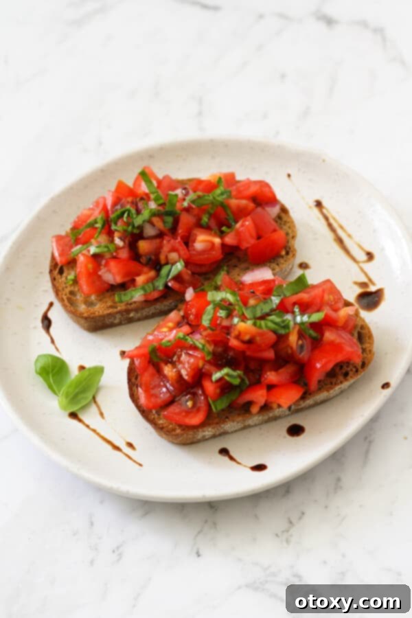 Effortless Bruschetta 6 Two vibrant bruschetta pieces on a clean white plate, artfully topped with fresh basil and generously glazed, ready to be served.