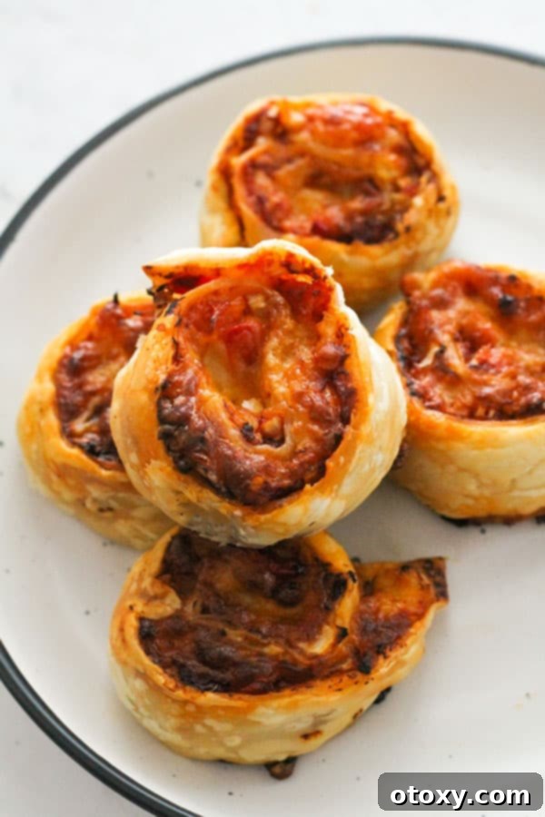 Golden brown pizza pinwheels arranged neatly on a pristine white plate, garnished with fresh basil.