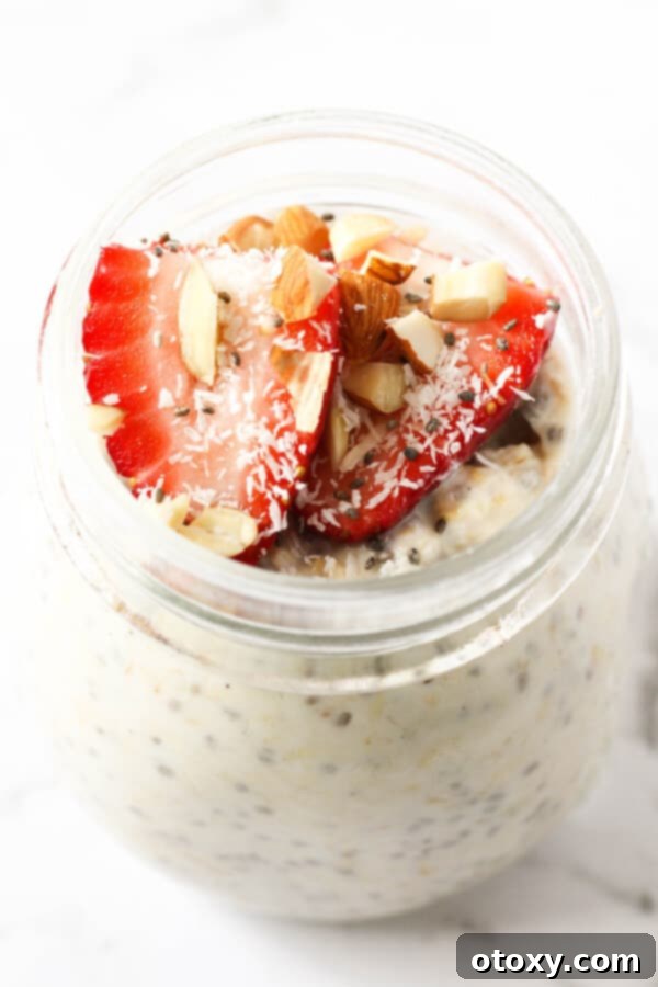 Nutritious Overnight Oats 6 A beautifully presented jar of overnight oats, artfully topped with fresh strawberries, delicate shredded coconut, and crunchy almond slivers, showcasing a perfect healthy breakfast.