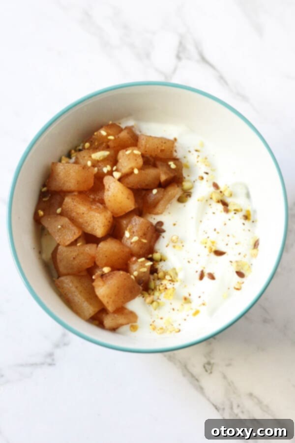 Creamy Greek yogurt beautifully topped with warm stewed cinnamon apples, creating a delightful and healthy breakfast or snack option.