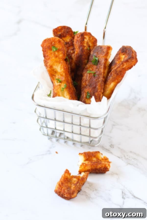 Halloumi fries arranged neatly in a rustic wire basket, showcasing their golden-brown, crispy exterior.