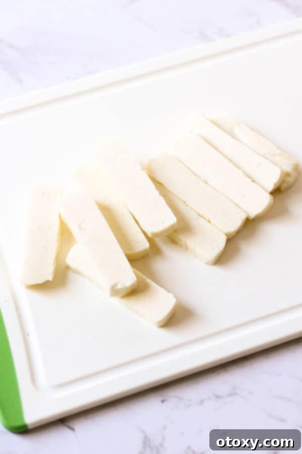 Precisely cut halloumi slices laid out on a clean cutting board, ready for the next step.