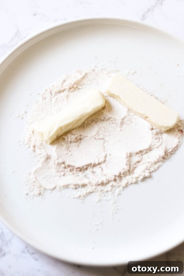 Halloumi slices being meticulously covered in a spiced flour mixture on a white plate, ready for frying.
