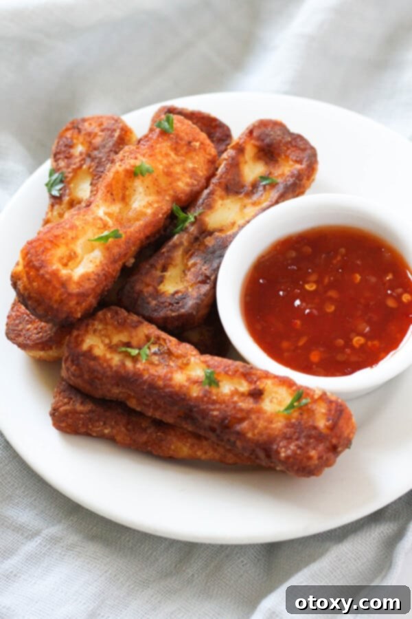 A beautifully presented plate of crispy halloumi fries, accompanied by a small bowl of sweet chili sauce for dipping.