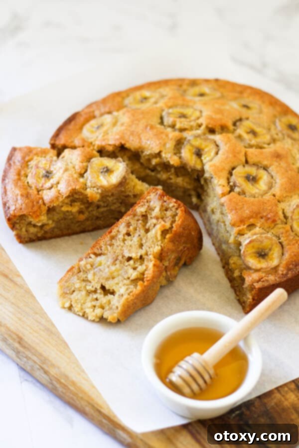 banana cake on a wooden board with a small bowl of honey.