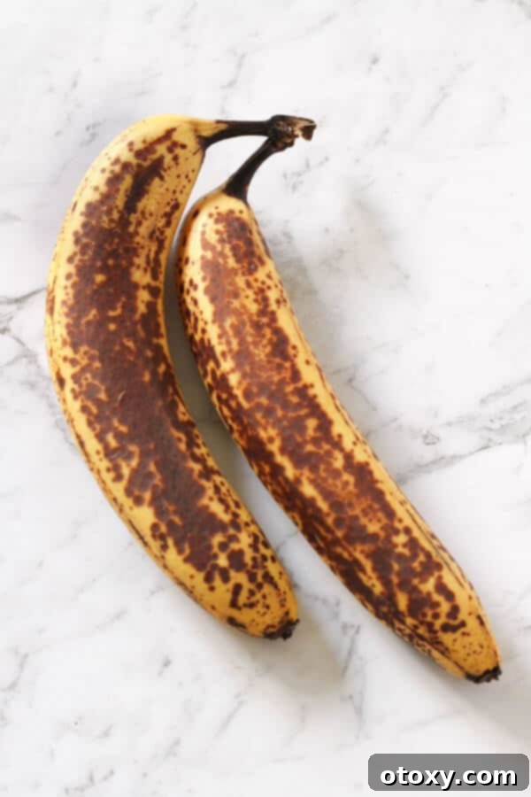 Two perfectly spotty, ripe bananas resting on a pristine white marble background, ideal for baking.