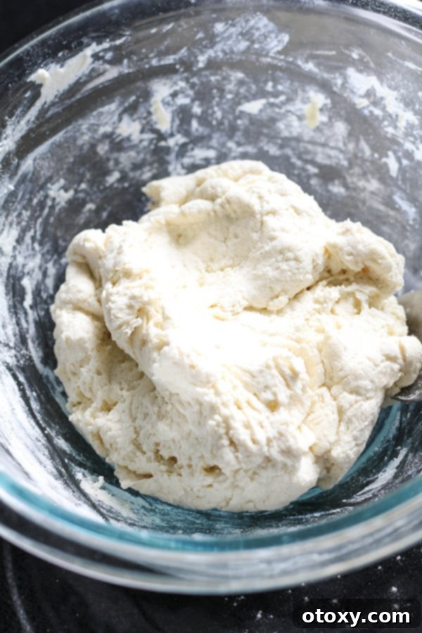 Thick Greek yogurt dough being mixed in a clear glass bowl.