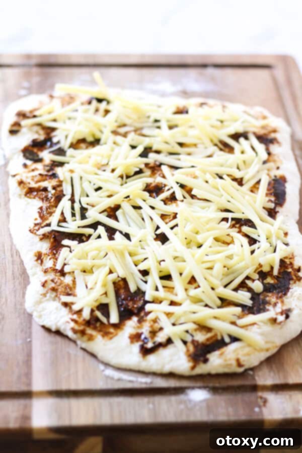 Vegemite Cheese Pinwheels 6 dough rolled out of a wooden cutting board topped with vegemite and cheese.