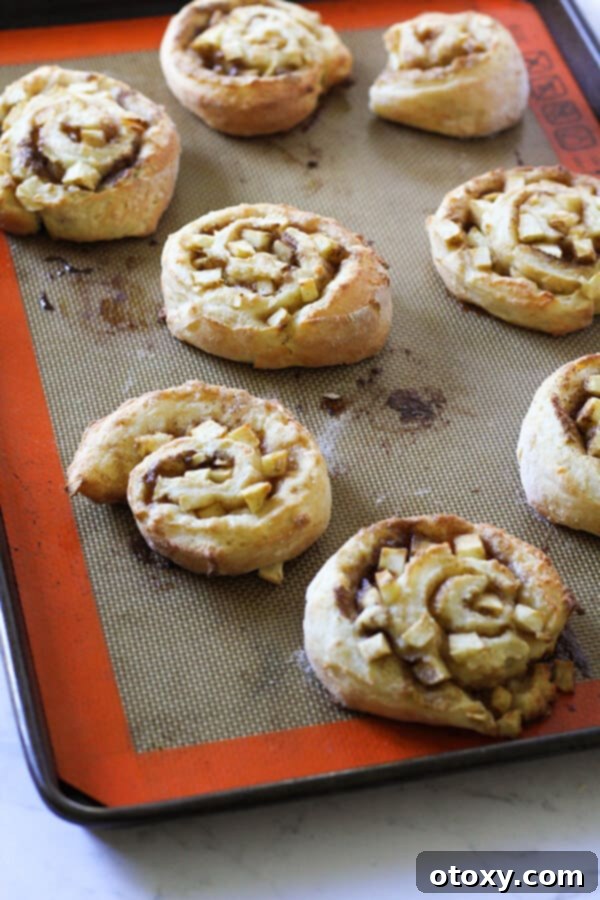 freshly baked apple cinnamon rolls on a baking tray.