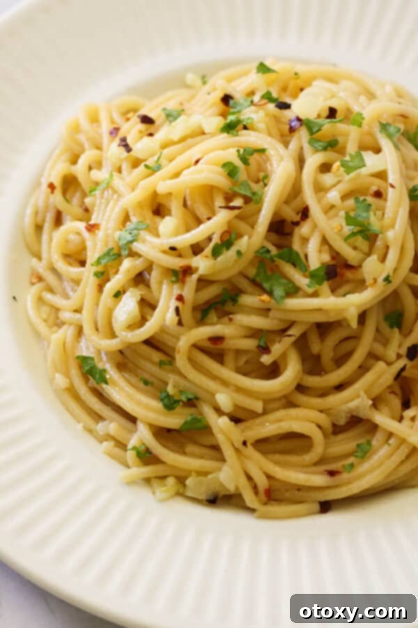 Spaghetti Aglio e Olio 2 Spaghetti with Garlic and Oil artfully plated on a white dish, garnished with fresh parsley.