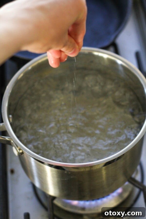 Classic Garlic and Olive Oil Spaghetti 4 Hand sprinkling salt into a saucepan of boiling water.