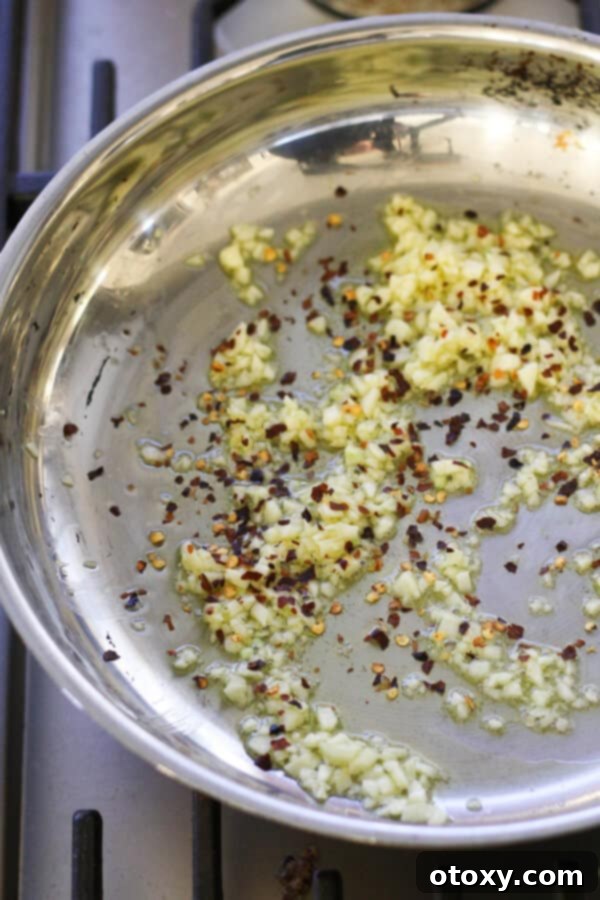 Classic Garlic and Olive Oil Spaghetti 6 garlic and red pepper flakes sautéing in a frying pan.