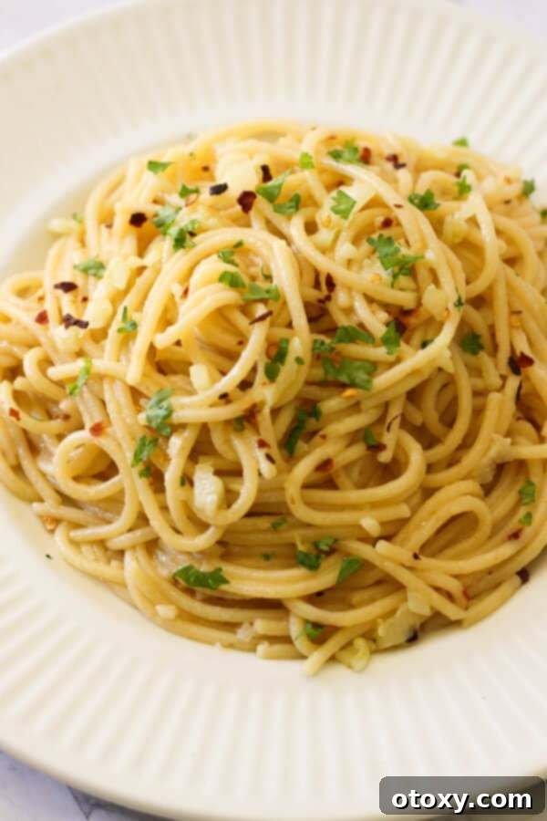 Spaghetti Aglio e Olio 9 A bowl of Spaghetti Aglio e Olio topped with fresh parsley and extra Parmesan cheese, ready to be enjoyed.