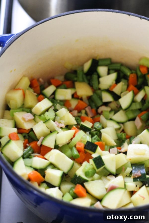 Adding diced potato, zucchini, and green beans to the sautéed aromatics and bacon in a Dutch oven, building layers of flavor for the Minestrone Soup.