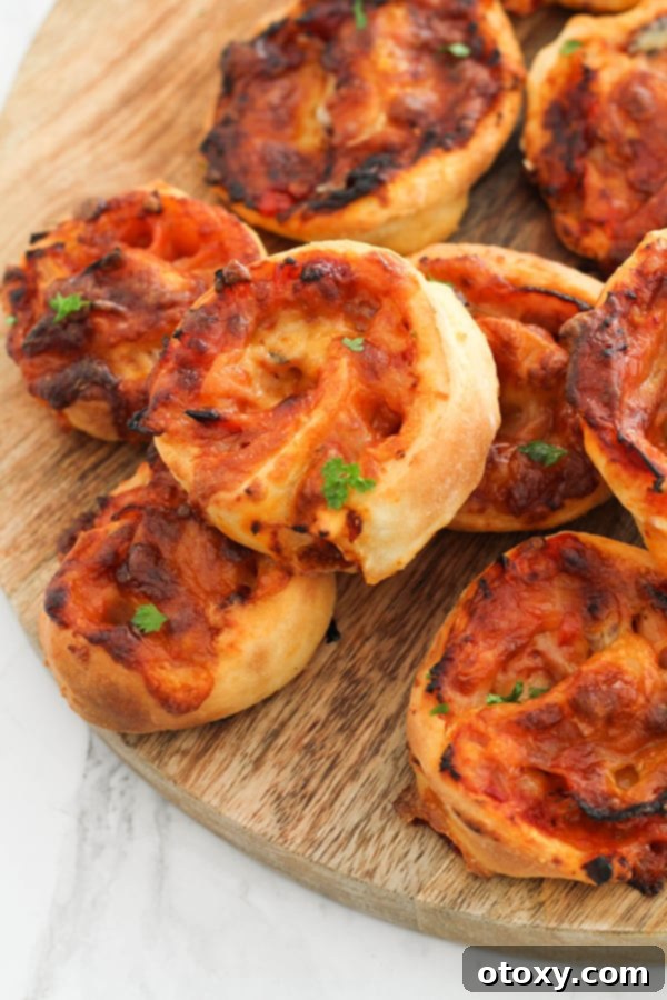 Pizza Pinwheels 12 pizza scrolls stacked together on a wooden board.