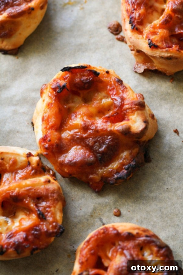 Pizza Pinwheels 4 pizza scrolls on a baking tray.