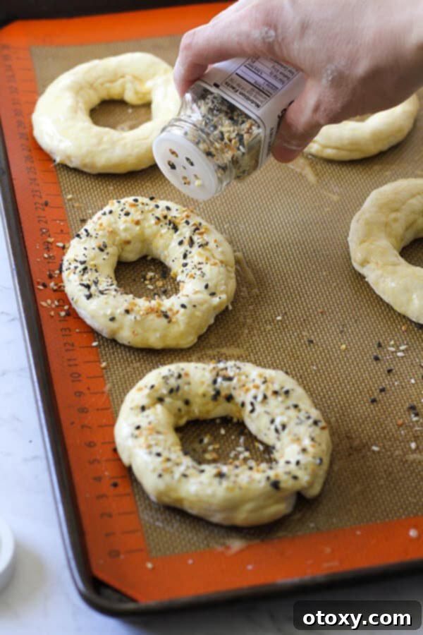 Speedy Yeast Free Bagels 9 Bagels on a baking tray being sprinkled with everything but the bagel seasoning after egg wash.