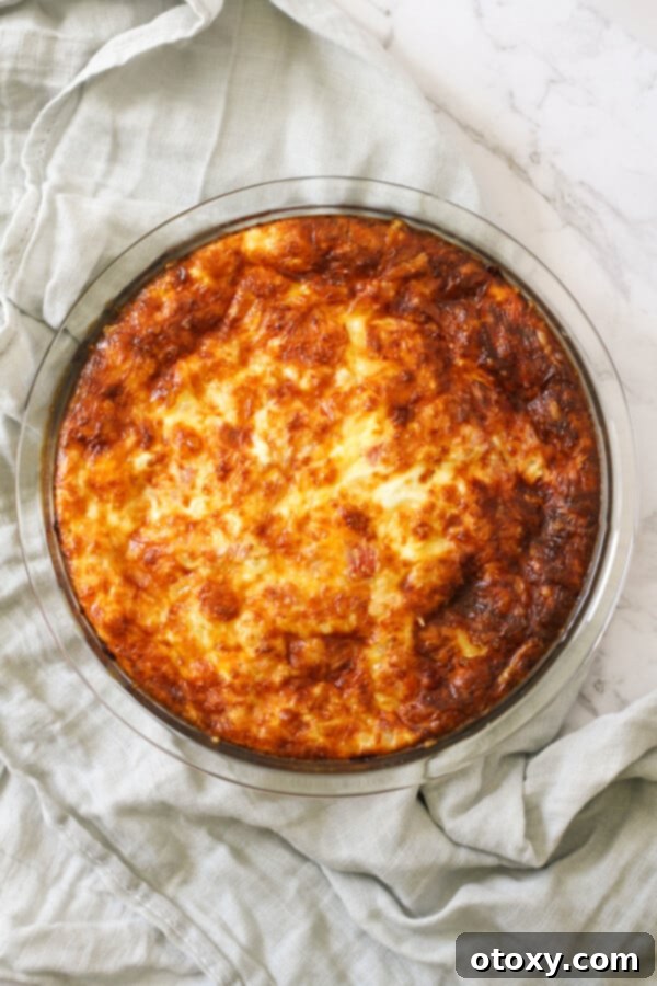 A perfectly baked Impossible Quiche, still in its glass pie dish, exuding warmth and deliciousness, with a golden-brown top.