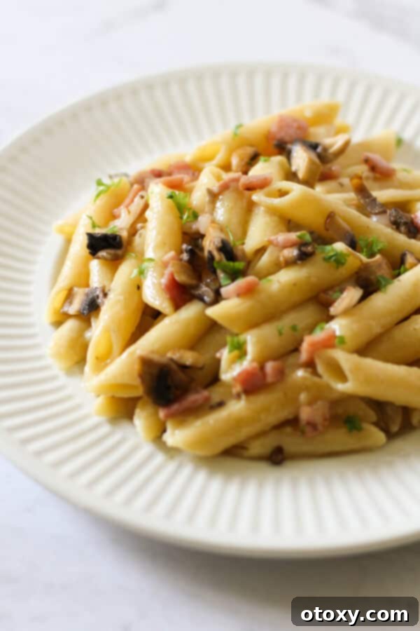 Creamy Carbonara on a white plate, garnished with fresh parsley.