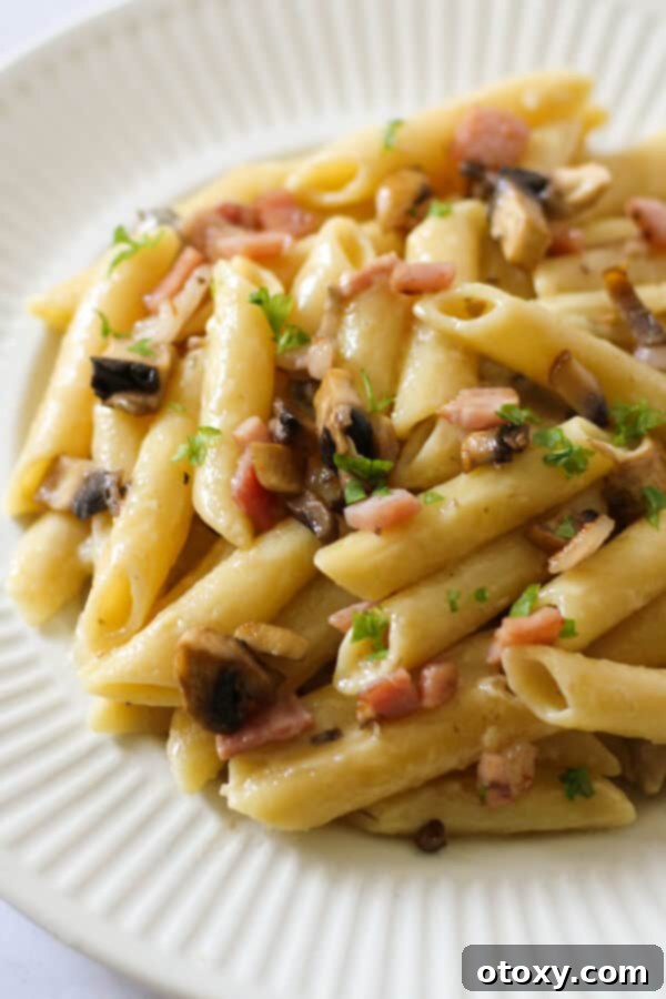 Creamy Carbonara on a white plate, garnished with fresh parsley.