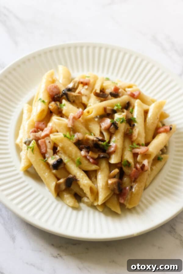 Creamy Carbonara on a white plate, ready to eat.
