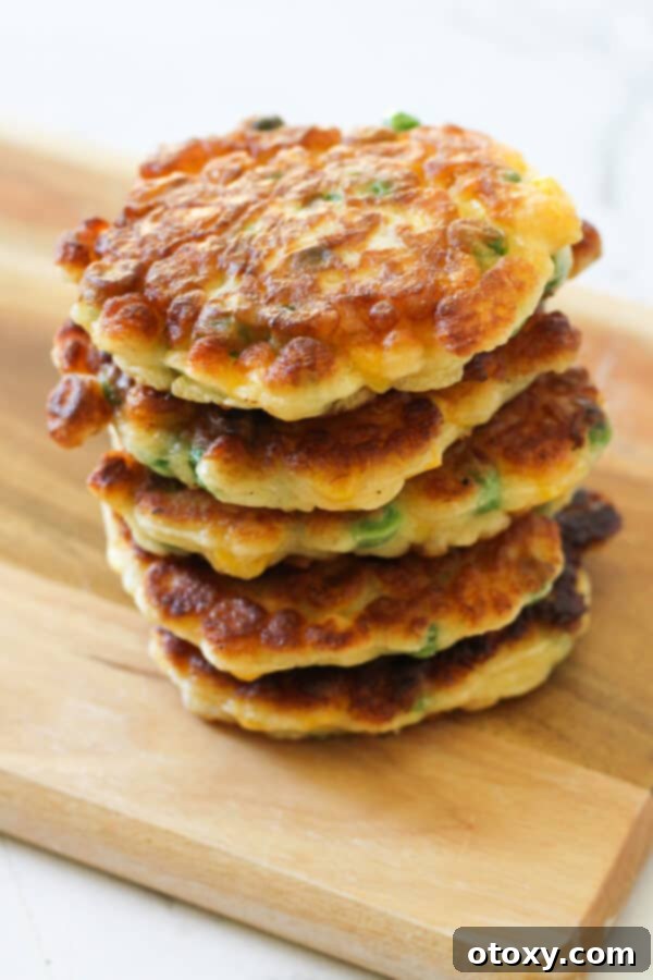 Vibrant Pea and Sweet Corn Fritters 7 Pea & Sweet Corn Fritters stacked elegantly on a wooden board, showcasing their inviting appearance.