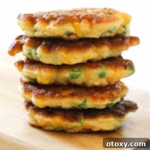 Vibrant Pea and Sweet Corn Fritters 8 Pea & Sweet Corn Fritters stacked on top of each other on a wooden board.