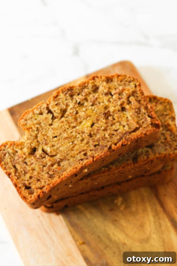 Velvety Buttermilk Banana Bread 11 A delicious loaf of Buttermilk Banana Bread, perfectly baked and sliced, resting on a wooden board, ready for storage or serving.