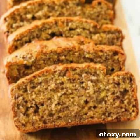 Velvety Buttermilk Banana Bread 12 Sliced buttermilk banana bread laying on a wooden board, showcasing its rich, moist interior.