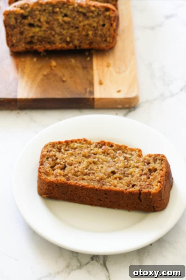 Velvety Buttermilk Banana Bread 4 A perfectly baked, golden-brown slice of moist Buttermilk Banana Bread resting on a pristine white plate.