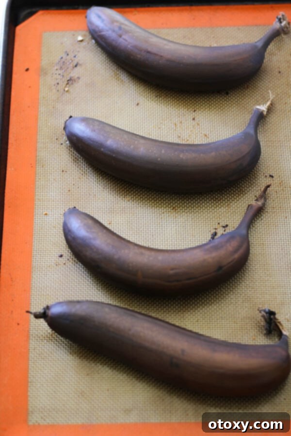 Velvety Buttermilk Banana Bread 5 Deeply roasted, caramelized bananas arranged on a baking tray lined with parchment paper, ready for banana bread.