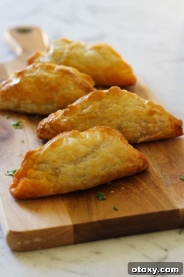 Delicious beef pasties arranged on a rustic wooden board, ready to be served.