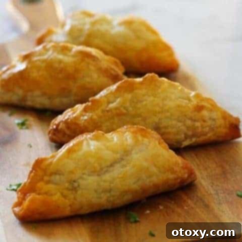 Golden-brown beef pasties arranged on a rustic wooden board.