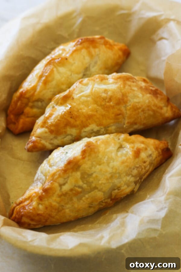 Several golden-brown beef pasties in a white serving dish, ready to be enjoyed.
