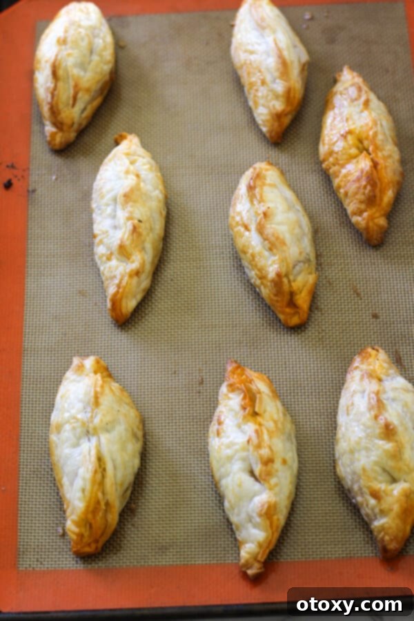 Golden-brown beef pasties, fresh out of the oven, steaming hot and ready to eat.