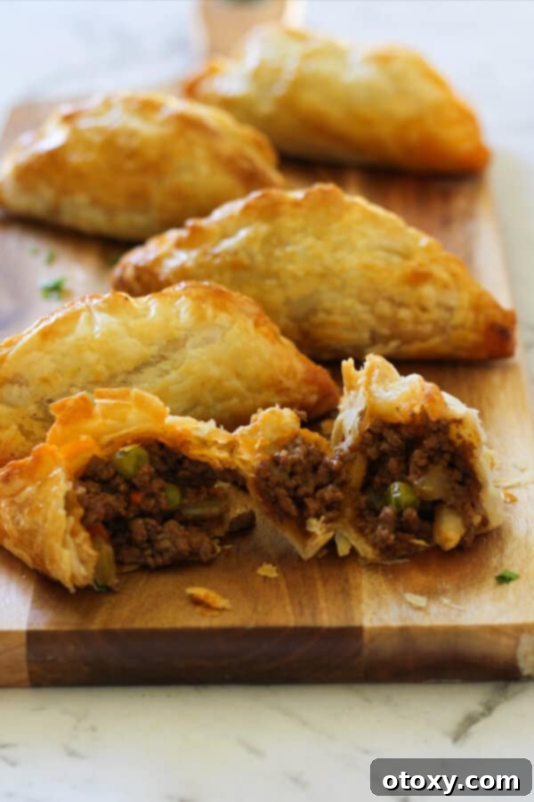 A close-up shot of several beef pasties on a wooden board, emphasizing their golden crust and hearty appearance.