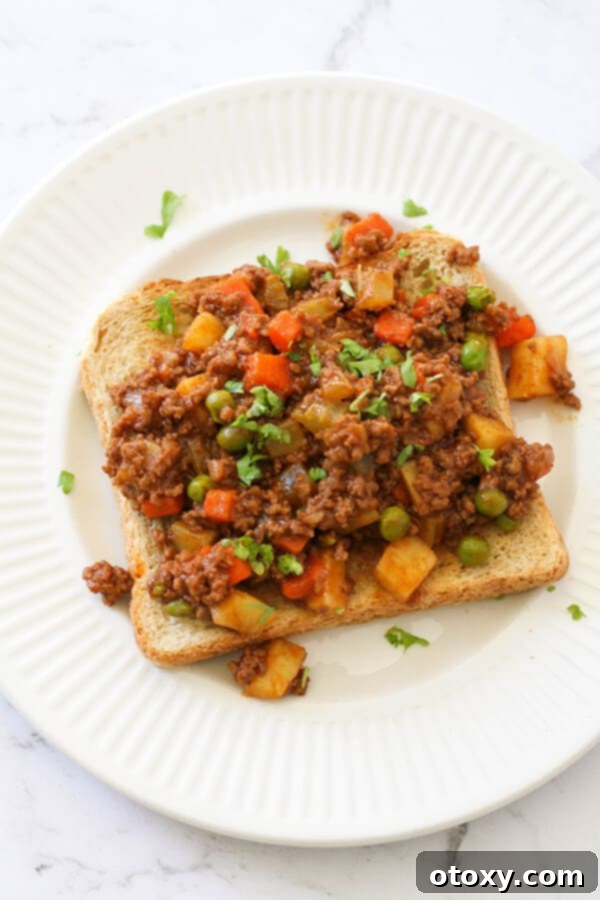 Savoury mince on top of a piece of toast on a white plate, showcasing a hearty and delicious meal.