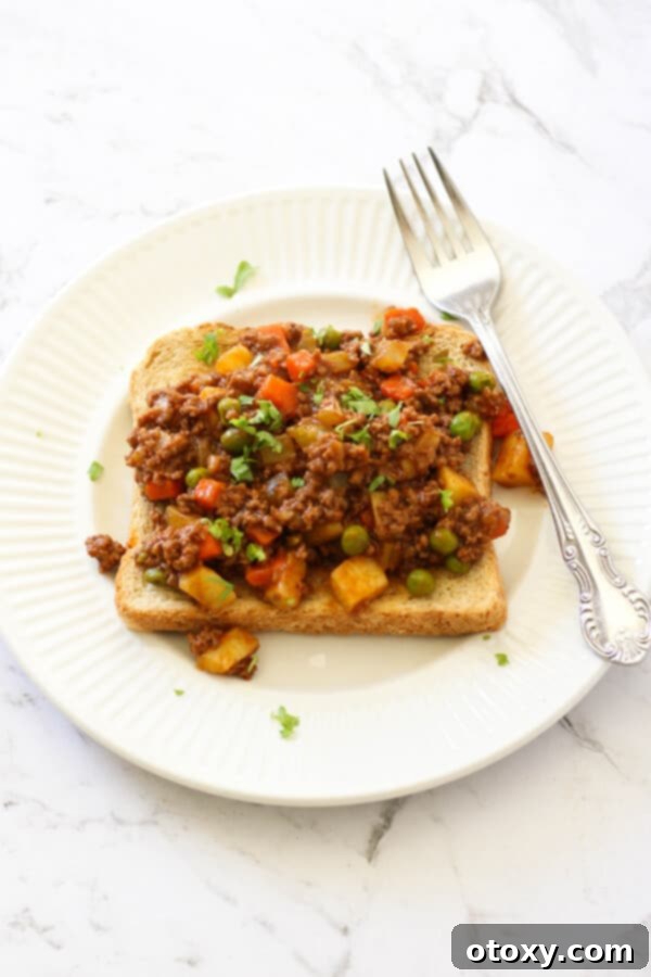 Savoury mince served on top of a piece of toast on a white plate, ready to be enjoyed.
