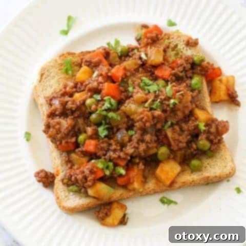 Savoury mince on top of a piece of toast on a white plate, ready to serve.