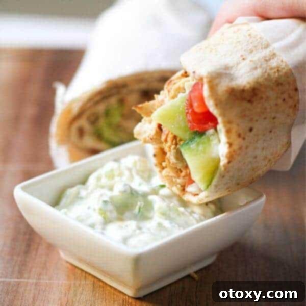 Flavorful Greek Chicken Gyros wrapped in warm pita bread, generously filled with marinated chicken, fresh salad ingredients, and creamy tzatziki sauce.