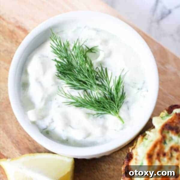 A bowl of creamy, refreshing Greek Tzatziki dip, garnished with fresh dill and a drizzle of olive oil, perfect for pita bread or gyros.